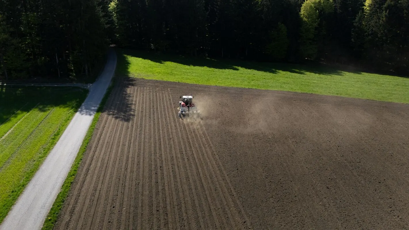 Traktor bei der Feldarbeit, Luftaufnahme mit Feldweg